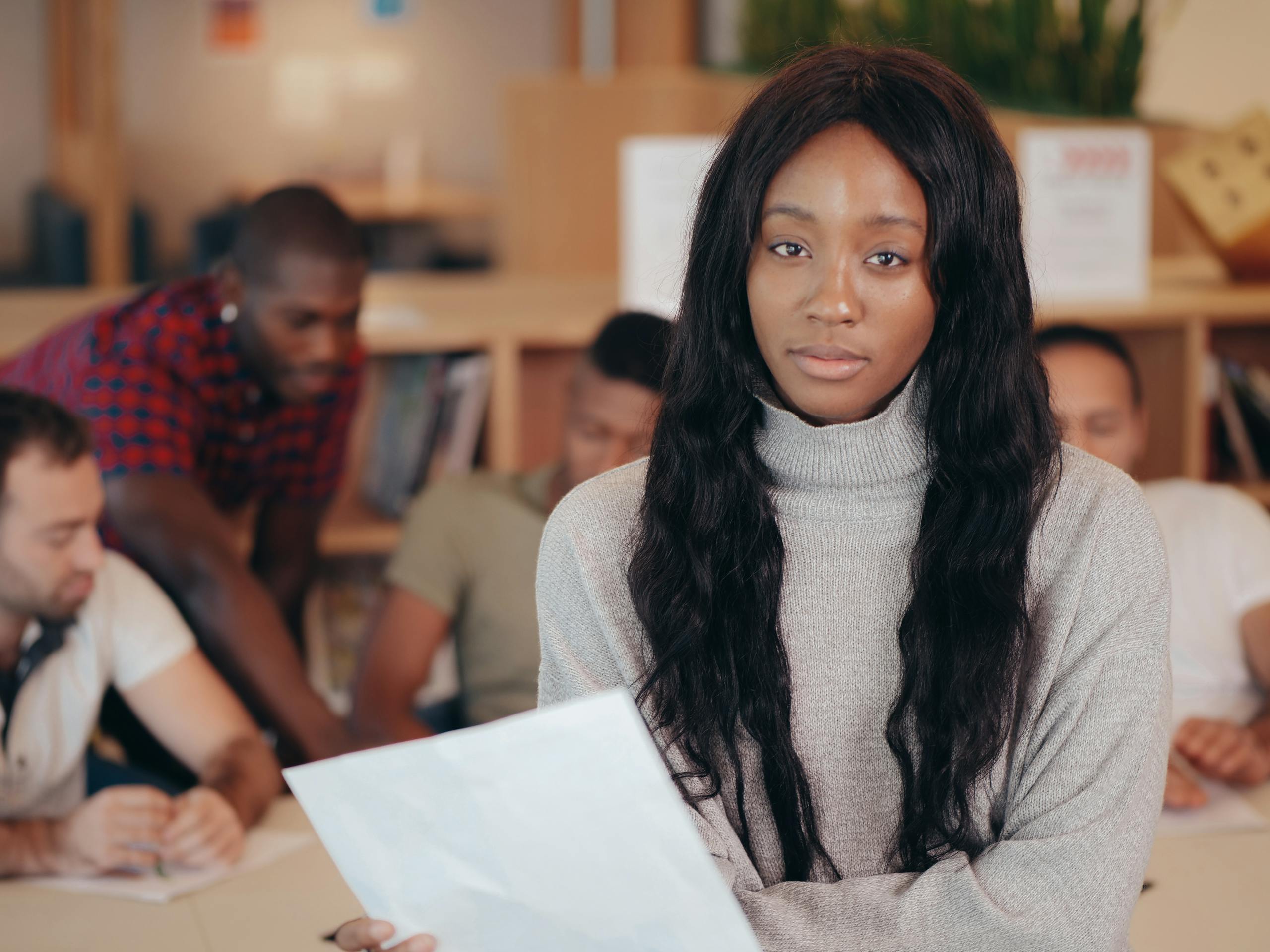 Female team member holding documents in a diverse office meeting.